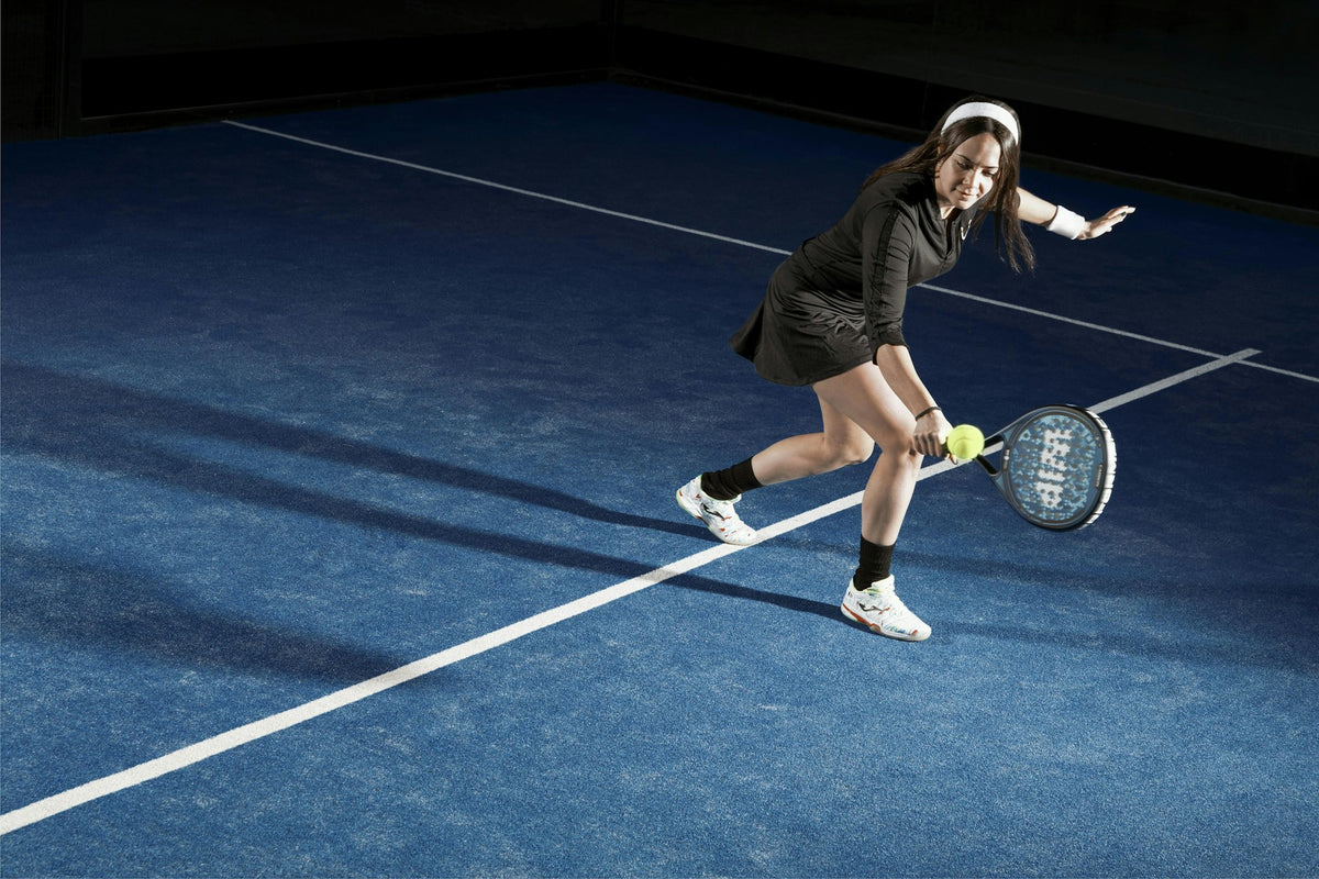 Padel player reaching for a low ball